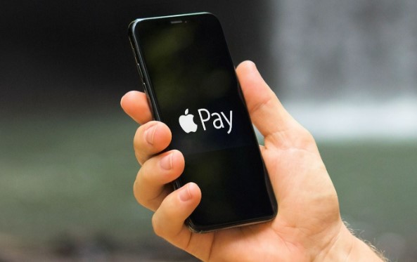 En mand holder en telefon op med Apple Pay på skærmen.