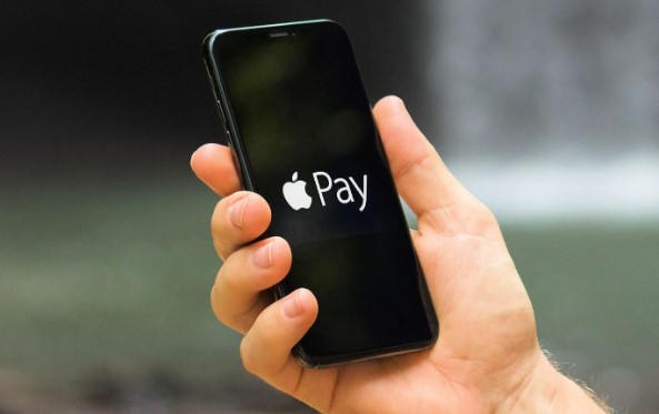 En mand holder en telefon op med Apple Pay på skærmen.